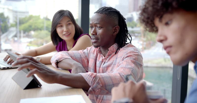 Collaborating in office, diverse team discussing project using tablet and documents stock video footage