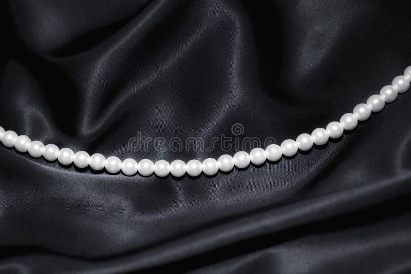 Collana di perle bianche su seta nera immagini stock