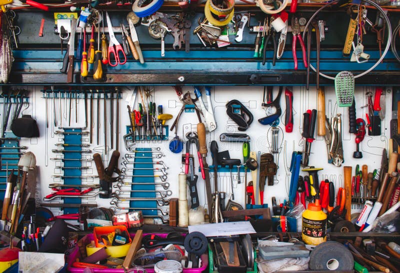 A collection of assorted tools hanging on the wall with a work bench