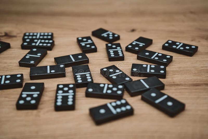 Scattered black domino tiles on wooden surface royalty free stock images