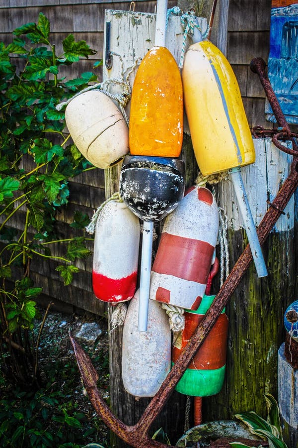 Collection of grungy colorful bouys tied to old post with rusty anchor royalty free stock photo