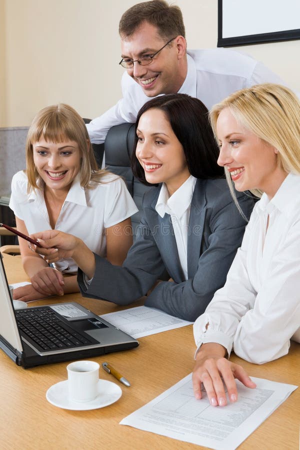 Collective job. Portrait of young businesswoman showing to the monitor of laptop and three businesspeople gathered together around the table with the laptop Collective job. Portrait of young businesswoman showing to the monitor of laptop and three businesspeople gathered together around the table with the laptop