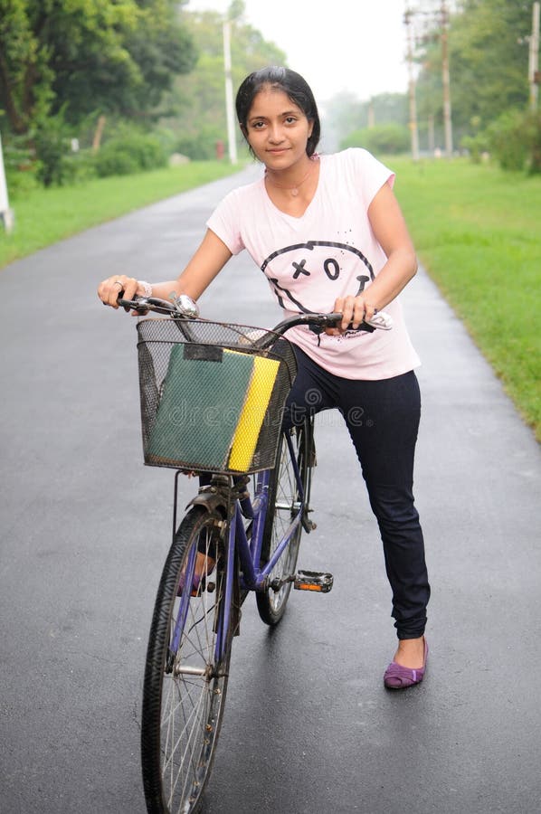 College girl on her cycle, at the middle of road.
