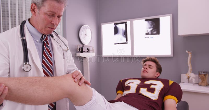 College sports athlete with mid aged doctor examining knee injury.