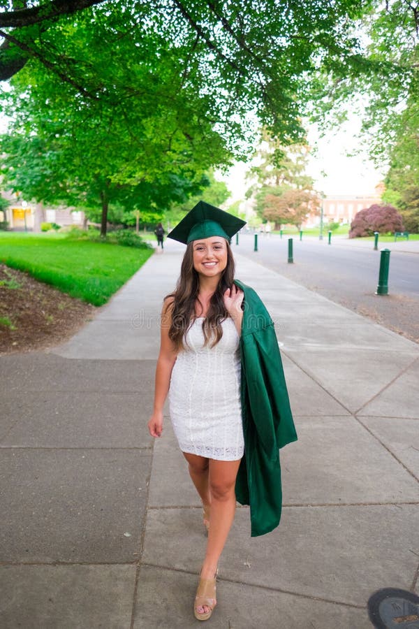 Female college student with her cap and gown heading towards the graduation ceremony on a university campus during the Spring in Oregon. Female college student with her cap and gown heading towards the graduation ceremony on a university campus during the Spring in Oregon.