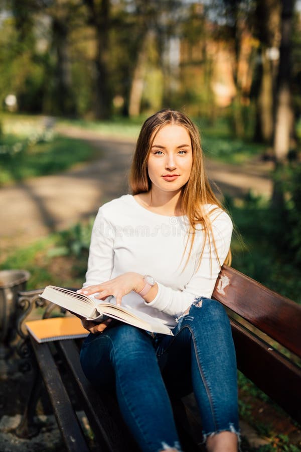 College Student Girl Reading a Book Sitting on Bench in City Park Stock ...