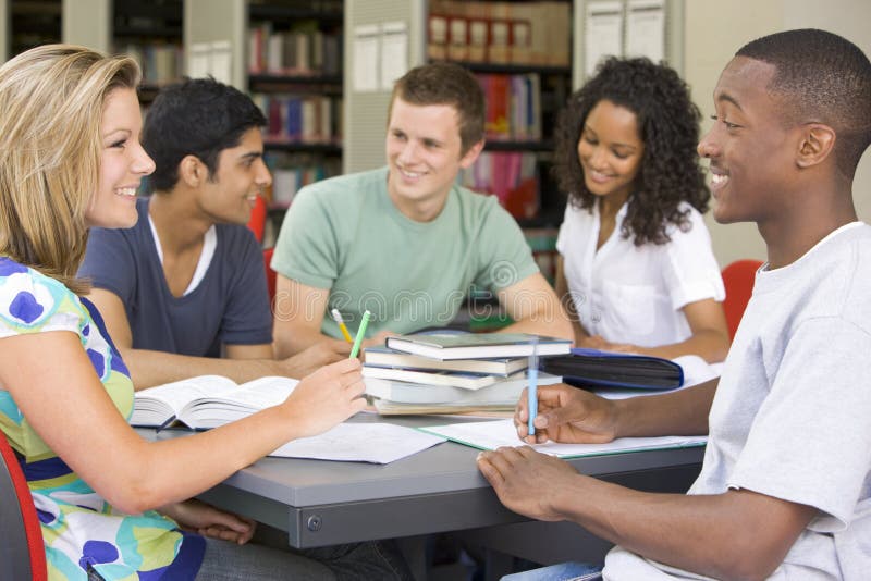 Vysokoškolští studenti studují společně v knihovně.