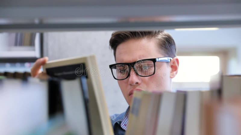 Collegebibliothek Männlicher Student, der nach Buch auf Bücherregalen sucht