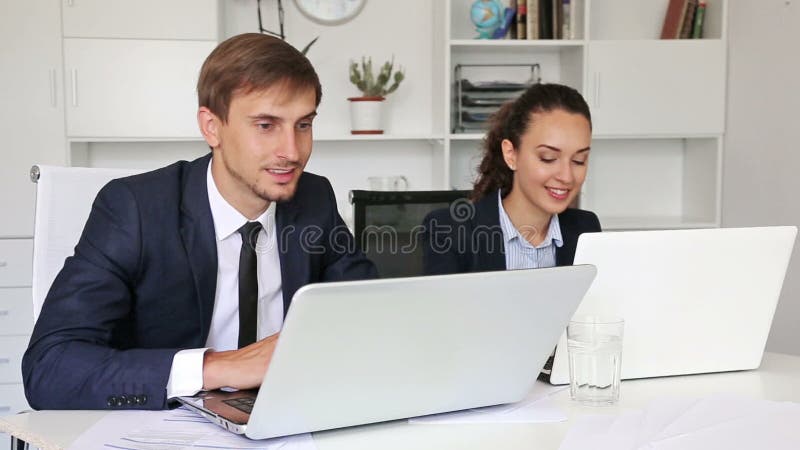 colleghi dell'uomo e della donna di affari che si siedono con i computer portatili