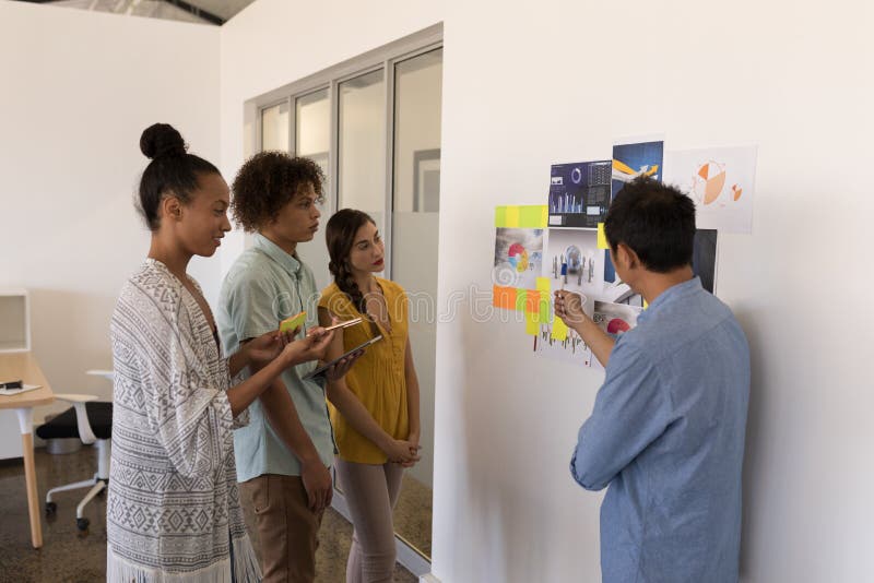 Colleghi di affari che discutono sopra i grafici e le note appiccicose nell'ufficio fotografie stock libere da diritti Colleghi di affari che discutono sopra i grafici e le note appiccicose nell'ufficio fotografie stock libere da diritti