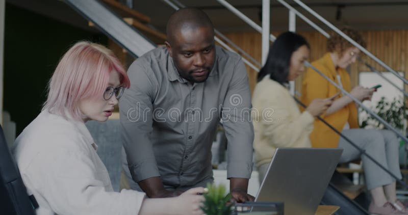 Colleghi di lavoro e colleghi di lavoro che parlano di documenti aziendali e computer portatile in ufficio