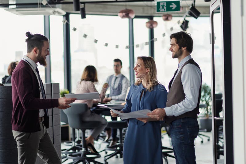 Collegues talking about project document, standing in modern office. stock photography
