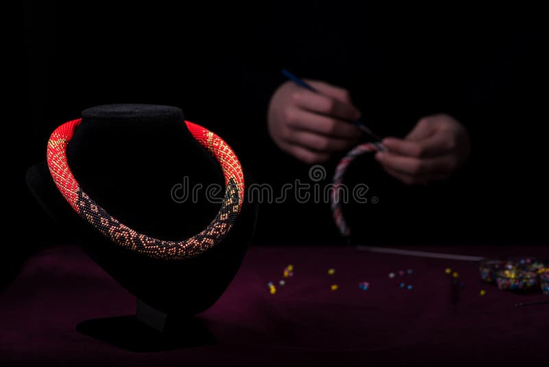 Collier multicolore des perles sur un mannequin Sur l'avion noir arrière la fille tricote les perles image stock Collier multicolore des perles sur un mannequin Sur l'avion noir arrière la fille tricote les perles image stock