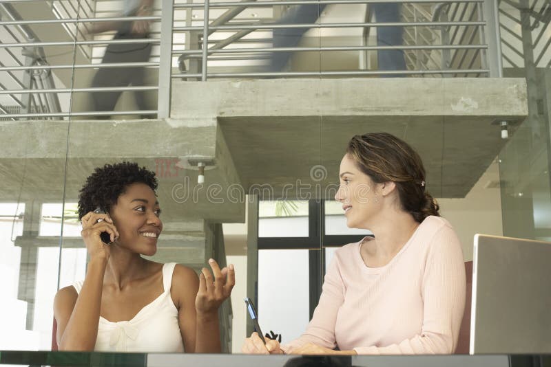 Collègue féminin d'On Call With de femme d'affaires notant vers le bas photos libres de droits