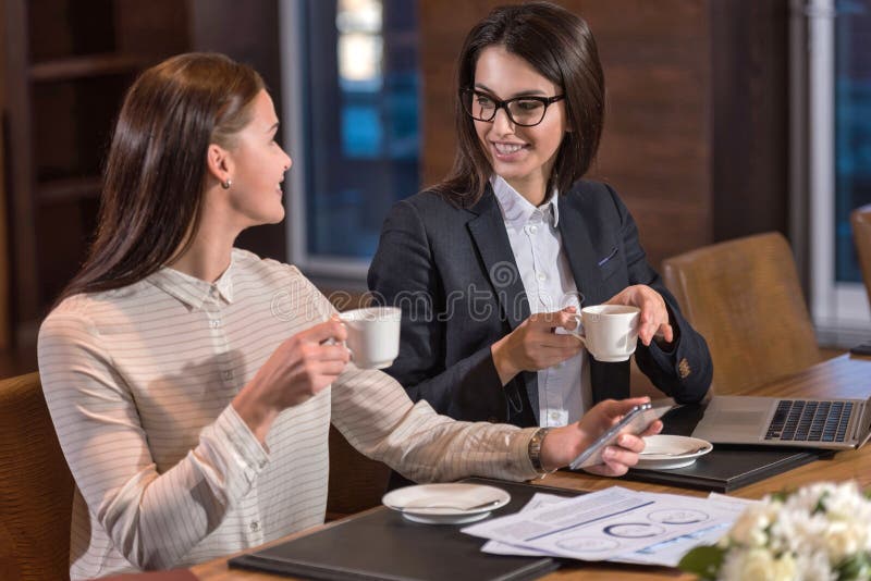 Collègues féminins avec plaisir buvant du thé dans un bureau image libre de droits Collègues féminins avec plaisir buvant du thé dans un bureau image libre de droits