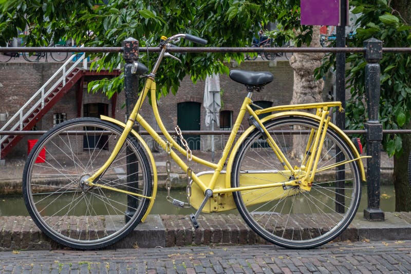 Color amarillo de la bici cerrado en un carril del canal del río en la ciudad de Utrecht, Países Bajos fotografía de archivo Color amarillo de la bici cerrado en un carril del canal del río en la ciudad de Utrecht, Países Bajos fotografía de archivo