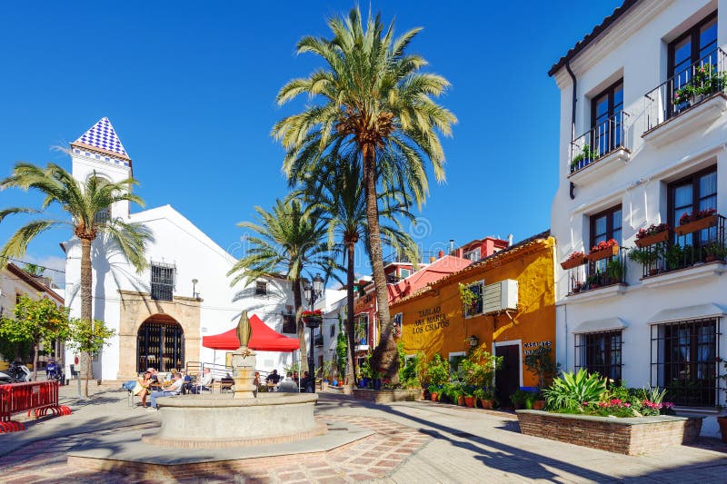 Color and bright yard with old white church and beautiful houses among green palms