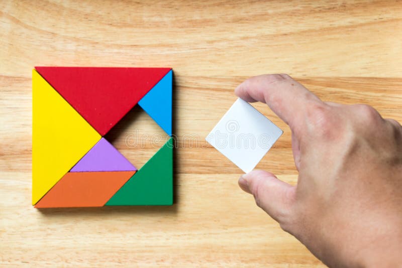 Color tangram puzzle in square shape that wait for fulfill on wood background