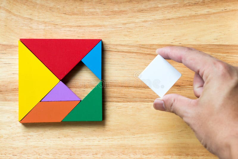 Color tangram puzzle in square shape that wait for fulfill on wood background