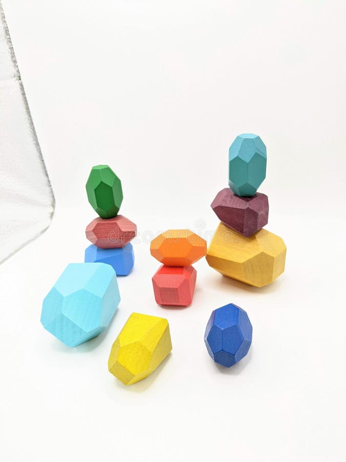 An original wooden toy rocks stand on top of each other. They are of all defferent colors: light blue, dark blue, brown, orange, yellow, green, purple. An original wooden toy rocks stand on top of each other. They are of all defferent colors: light blue, dark blue, brown, orange, yellow, green, purple.