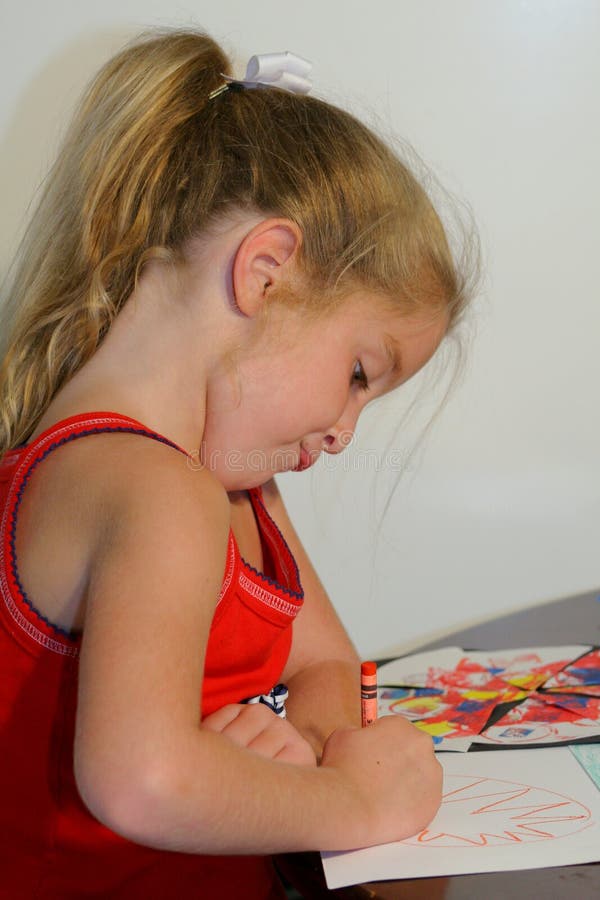 Young child coloring on a piece of paper making a funny face. Young child coloring on a piece of paper making a funny face