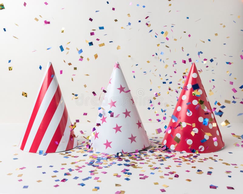 Colored confetti and party hat on white background. Minimal party concept royalty free stock image Colored confetti and party hat on white background. Minimal party concept royalty free stock image