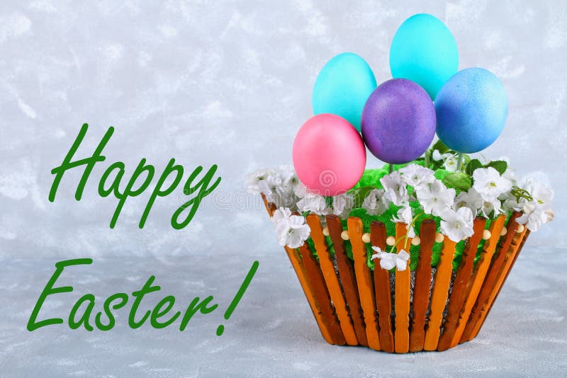 Colored Easter Eggs in a Basket on a Gray Concrete Background. Stock