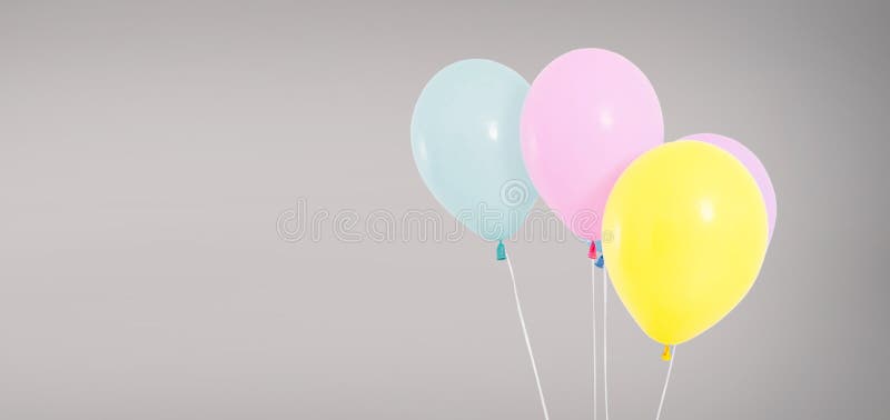 Colored helium balloons isolated on grey background, birthday concept .