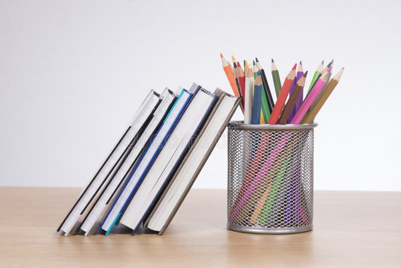 Colored pencil crayons with textbooks for school