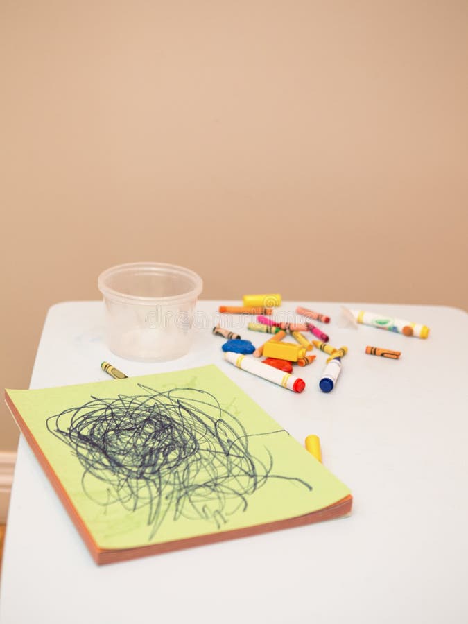 Colored pencils and markers with album drawing on white children table