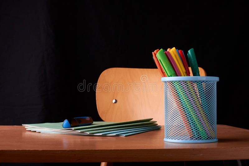 Colored Pens in a blue metal basket on desk in school