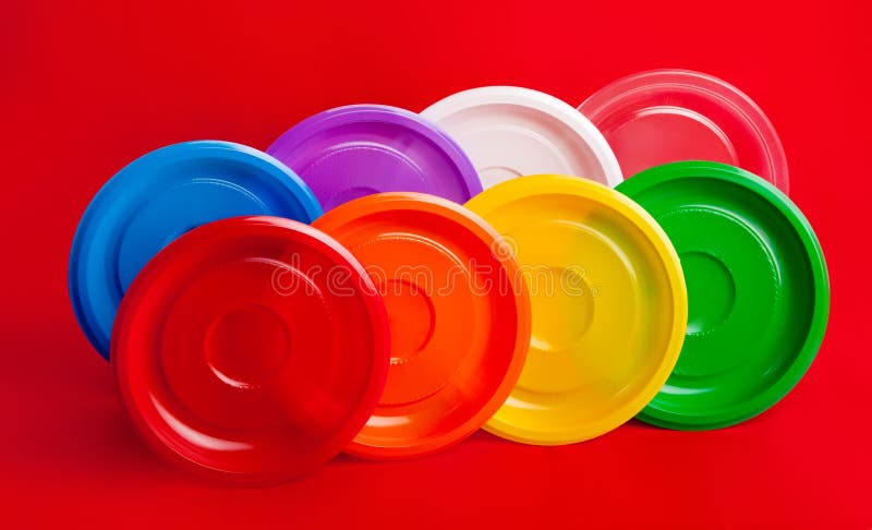 Colored plastic utensils on red background stock images