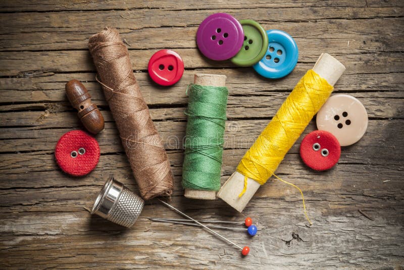 Colored Sewing Buttons and Bobbin Threads on Wooden Background Stock