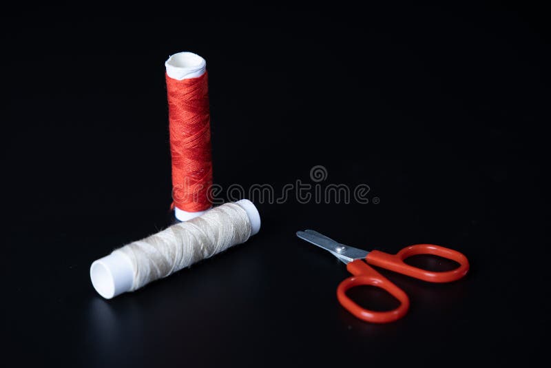 Red yarn roller and thread on black background