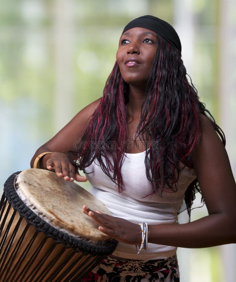 An African woman plays the djembe drum. An African woman plays the djembe drum