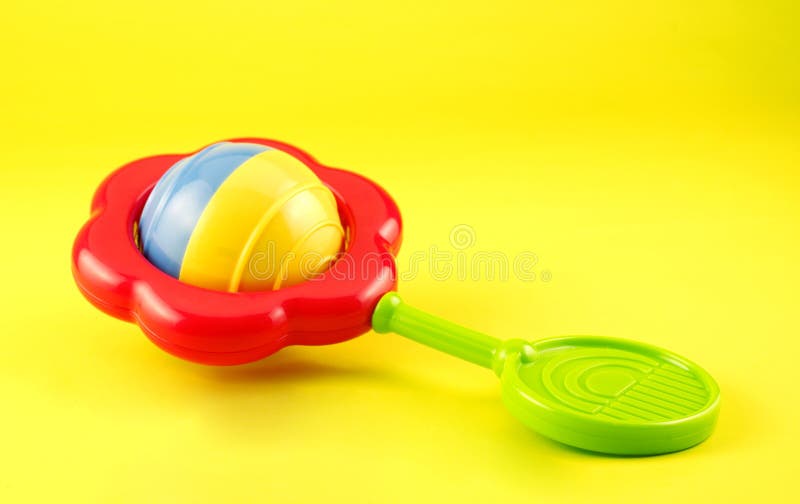 Colorful Baby Rattle on Yellow Background royalty free stock photos
