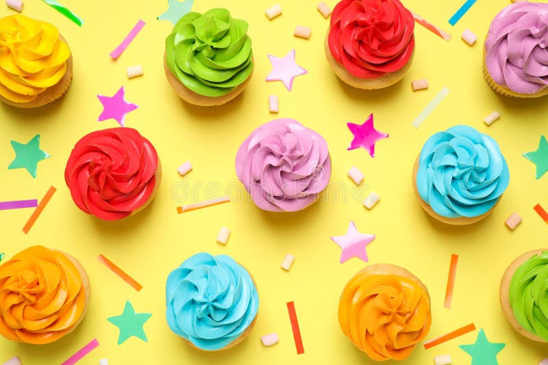 Colorful birthday cupcakes on yellow background, flat lay stock photo Colorful birthday cupcakes on yellow background, flat lay stock photo