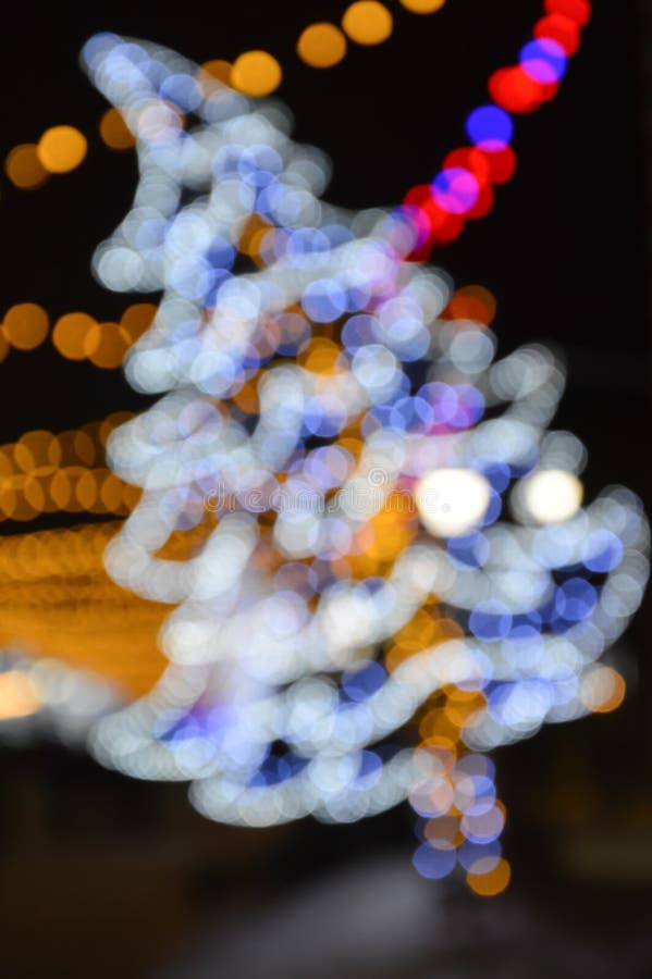 Colorful bokeh lights in the shape of a Christmas tree. Beautiful festive shiny background for celebrating Merry Christmas and Happy New Year. A bright decoration of the city for winter holidays. small circles. Colorful bokeh lights in the shape of a Christmas tree. Beautiful festive shiny background for celebrating Merry Christmas and Happy New Year. A bright decoration of the city for winter holidays. small circles.