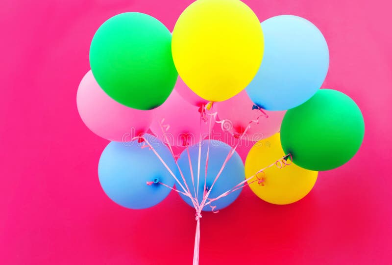 Colorful bundle of air balloons on pink background closeup