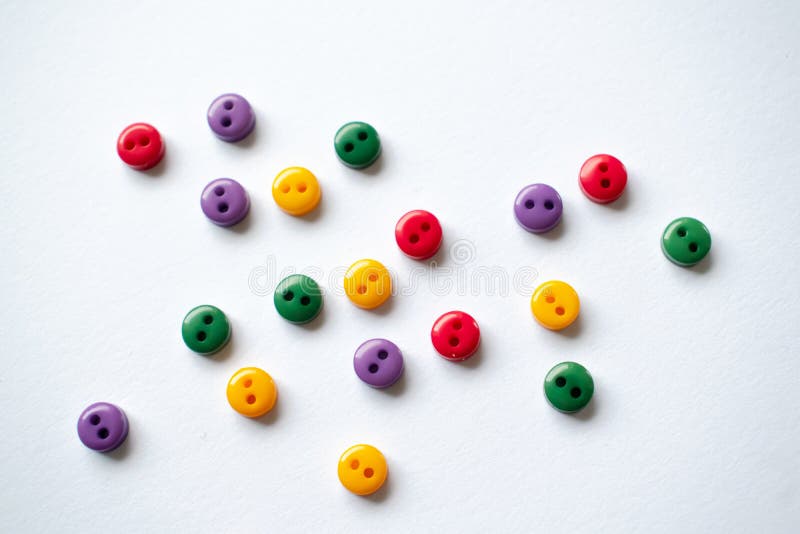 Colorful buttons on white background, red, yellow green blue or violet button, tiny little buttons closeup