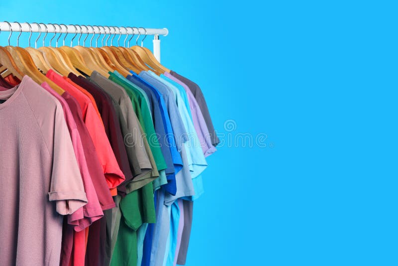 Colorful Clothes Hanging on Rack Against Blue Background. Space for Text  Stock Photo - Image of space, clothing: 168578462