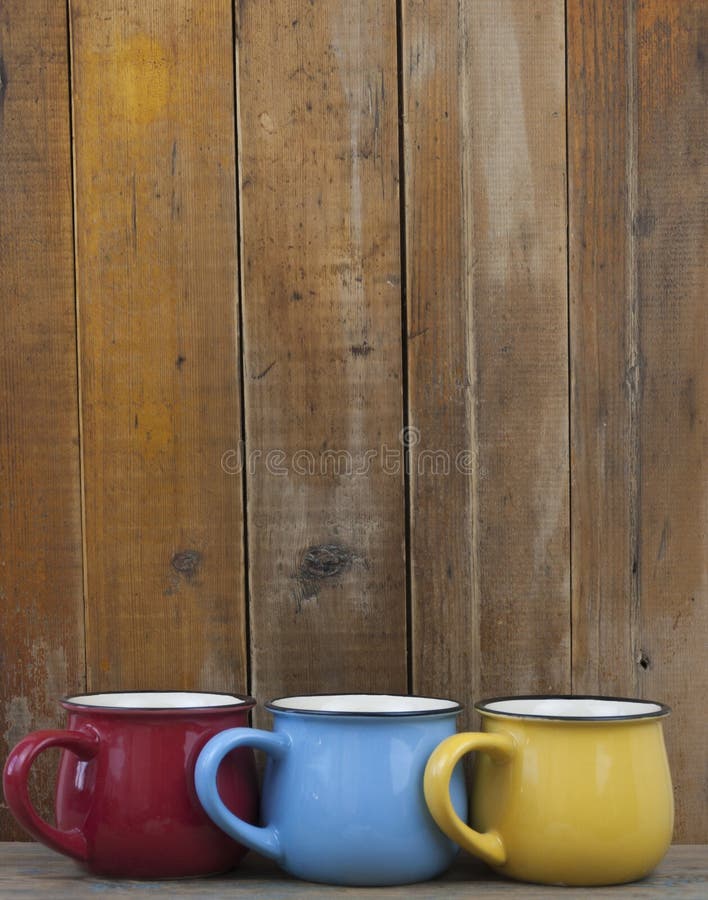 Colorful coffee cups on wooden table over grunge background