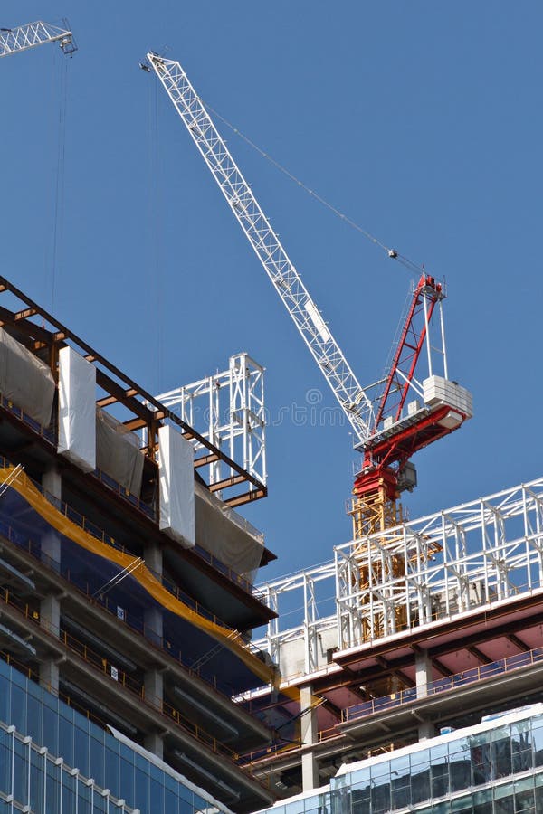Colorful Construction. Red,yellow and white crane rises above a high-rise building under construction, against a bright blue sky royalty free stock photos Colorful Construction. Red,yellow and white crane rises above a high-rise building under construction, against a bright blue sky royalty free stock photos