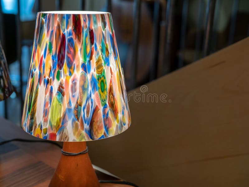 Colorful Desk Lamp with Soft Glow Sitting on Table Near Railing Stock