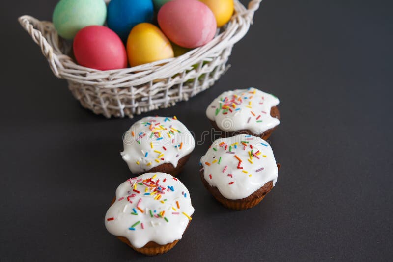 Colorful Easter eggs in basket and sweet muffins cupcakes on a black background. Easter background stock photo Colorful Easter eggs in basket and sweet muffins cupcakes on a black background. Easter background stock photo