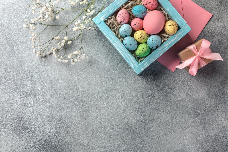 Colorful easter eggs in box and gift on table. Top view with copy space