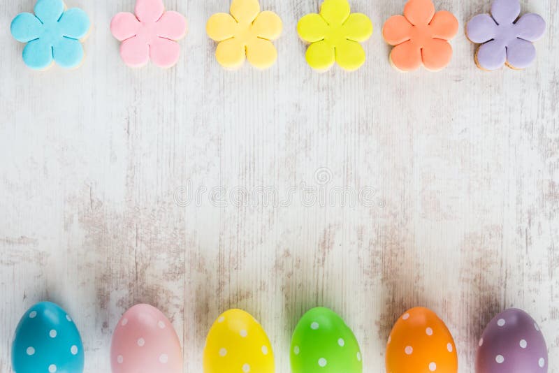 Colorful easter eggs and homemade fondant covered flower cookies on a white wood background royalty free stock image Colorful easter eggs and homemade fondant covered flower cookies on a white wood background royalty free stock image