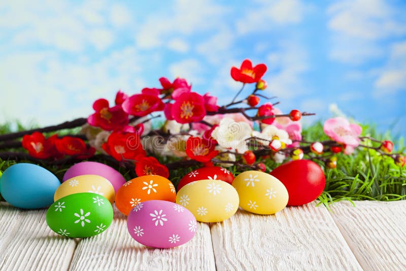 Colorful Easter eggs on wooden table and branch with flowers on grass and blue sky background royalty free stock photo Colorful Easter eggs on wooden table and branch with flowers on grass and blue sky background royalty free stock photo