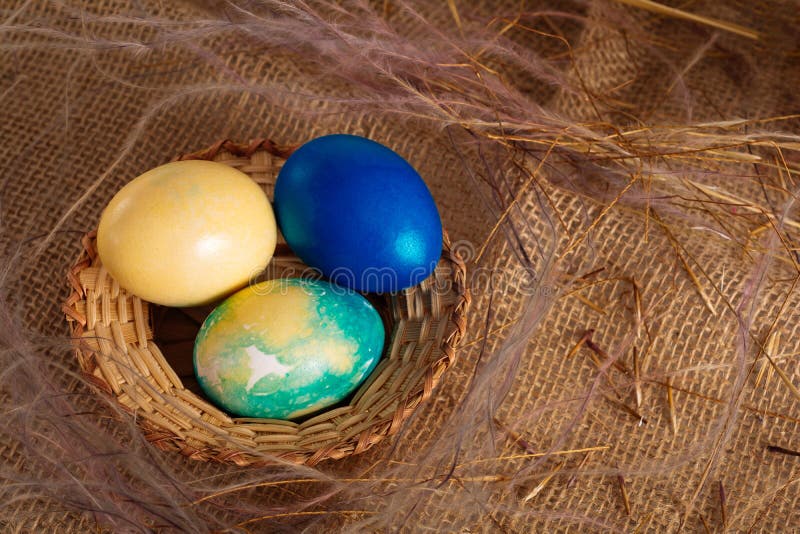 Colorful Easter eggs yellow, blue and blue colors in a wicker basket on a brown cloth background. Close up stock images Colorful Easter eggs yellow, blue and blue colors in a wicker basket on a brown cloth background. Close up stock images