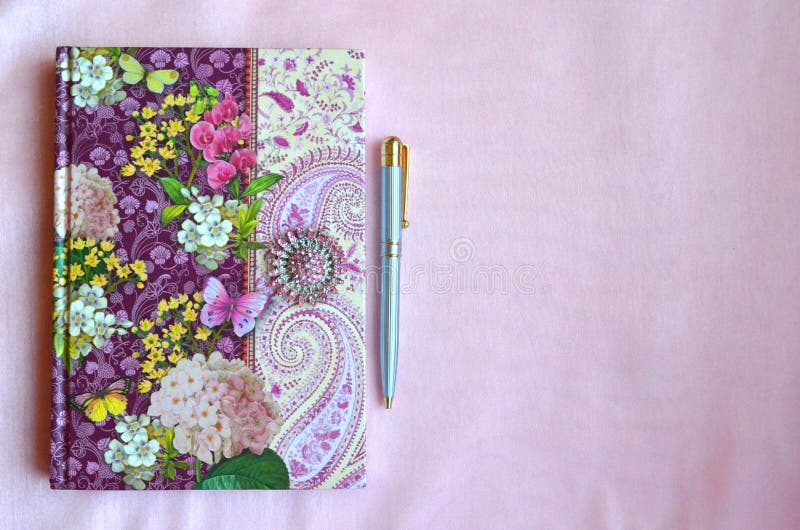 Colorful floral notebook on a light pink silk background with copy space